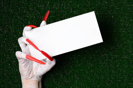 A scary halloween vampire with sharp claws holding a blank card with copy space.の写真素材