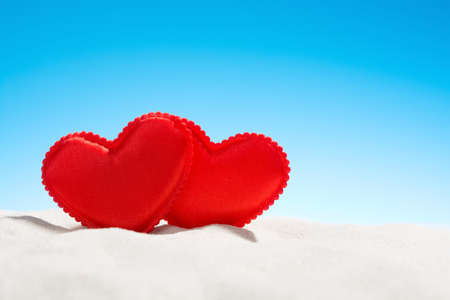 Two small red hearts on the beachの写真素材