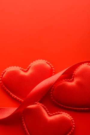 From above small fabric hearts and ribbons on red background.の写真素材