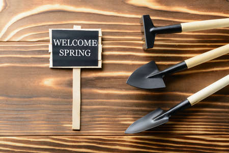 From above Welcome Spring sign and tools for gardening on wooden tableの写真素材