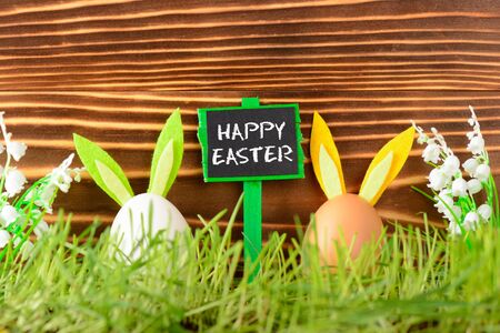 Two Eggs with decorative bunny ears and greeting sign Happy Easterの写真素材