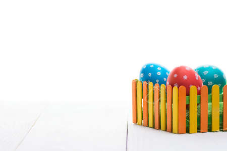 Composition of eggs for Easter behind a colorful fence on a wooden table