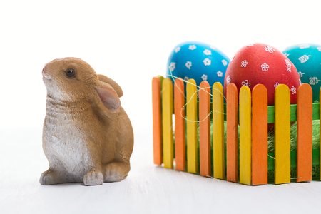 Composition with Easter eggs on the fence and the rabbit on wooden backgroundの写真素材