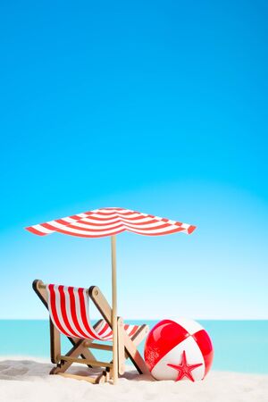 Lounge chair with parasol and beach ball on the coast, sky with copy spaceの写真素材