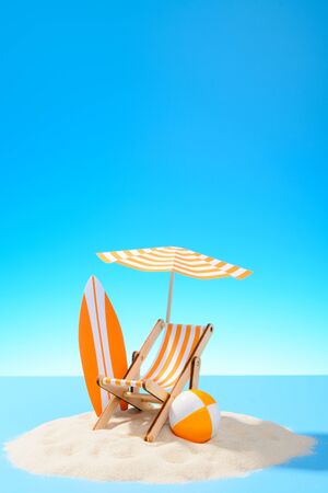 Paradise island in the ocean. Miniature beach accessories for outdoor activities. Blue background with copy spaceの写真素材