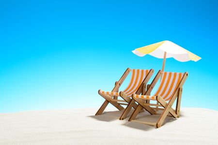 Two chaise longue under an umbrella on the sandy beach, sky with copy spaceの写真素材