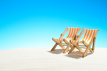 Two sun loungers on the sandy beach and the sky with copy spaceの写真素材
