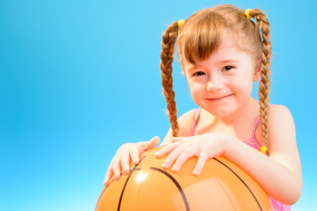 Cute little girl with the big inflatable beach ballの写真素材