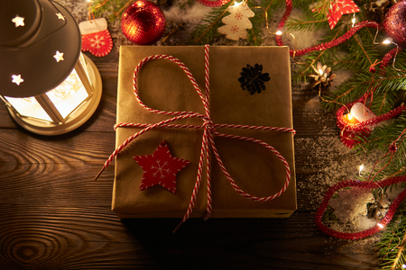From above shot of composed wrapped present with twine on table with burning lantern and garland for Christmasの写真素材