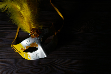 Closeup shot of Purim carnival glowing silver mask with gold ornament on wooden tableの写真素材