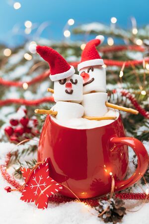 Red mug with hot chocolate and two snowmen in love made from marshmallows. Christmas and New Year composition.の写真素材