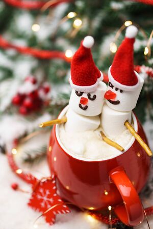 Red mug with hot chocolate and two snowmen in love made from marshmallows. Christmas and New Year composition.の写真素材