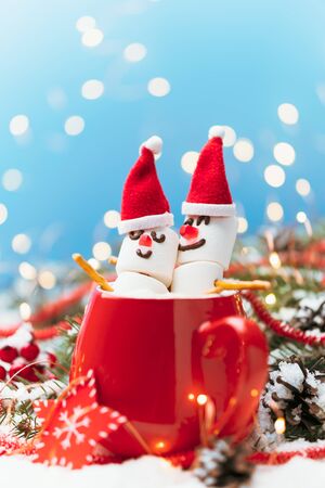 Red mug with hot chocolate and two snowmen in love made from marshmallows. Christmas and New Year composition.の写真素材