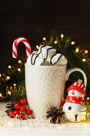 Sweet marshmallows and candy in a white ceramic mug on a wooden table with Christmas and New Year decorations. Festive composition.の写真素材