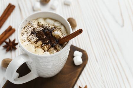 White mug with hot chocolate and marshmallows with cinnamon stick on a wooden table. Hot winter drink, top view.の写真素材