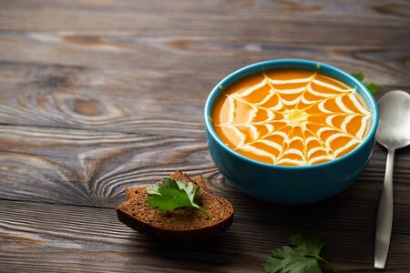 A healthy pumpkin puree garnished with cream and parsley leaves. Autumn cream soup for the holiday Halloween on a dark wooden backgroundの写真素材