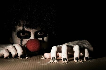 A terrible creepy clown peeps out of the basement and scratches the floor with his claws.の写真素材