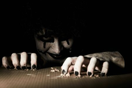 A terrible creepy clown peeps out of the basement and scratches the floor with his claws.の写真素材