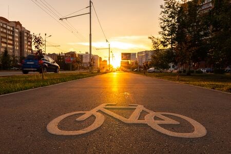 White bike sign on a bike path in the city at sunset.の写真素材