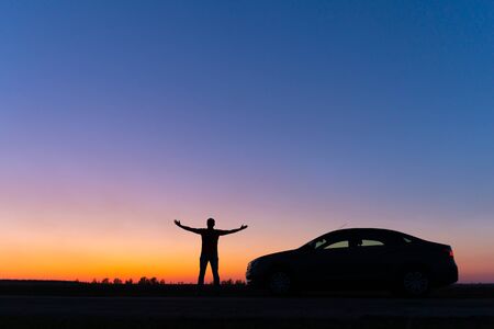 Silhouette of a man and a car on a background of a very beautiful sunset. Freedom and travel by car concept.の写真素材