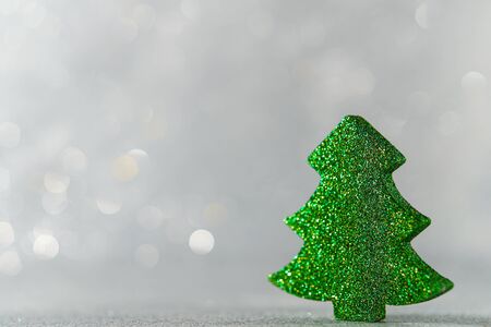 Decorative figurine of a Christmas tree toy on a silver bokeh background. The empty space on the left.の写真素材