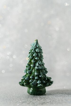 Decorative figurine of a Christmas tree toy on a silver bokeh background.の写真素材