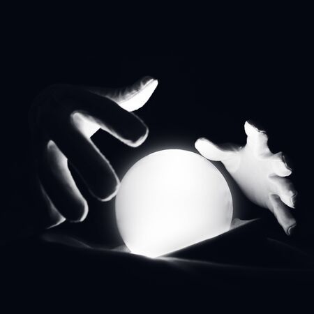 Spiritual session predicting the future. Open hands in white gloves over a luminous crystal ball.の写真素材