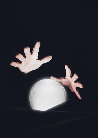 Mans hands over a magic crystal ball on a black background. Session for predicting the future.の写真素材