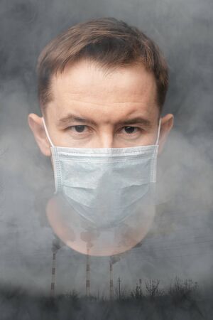 Double exposure of a man in a protective mask and dirty smoke from the exhaust pipes of a production. The concept of air pollution by toxic gases.の写真素材