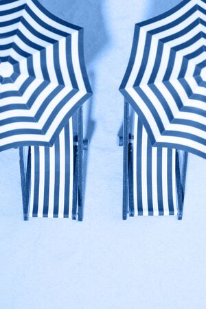 Top view of striped chairs under umbrellas on beach. Toning in trendy color 2020 classic blue.の写真素材
