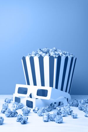 Cinema concept of 3D glasses and snacks scattering near paper cup on white board on the grey background. Toning in trendy color 2020 classic blue.の写真素材