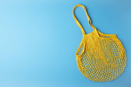 Zero waste concept. A reusable mesh yellow shopping bag on blue background. Horizontal orientation with copy space, top view.の写真素材