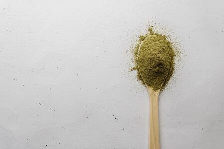 A wooden spoon with hemp flour lies on a light concrete table. Image with space for copy, top view.の写真素材