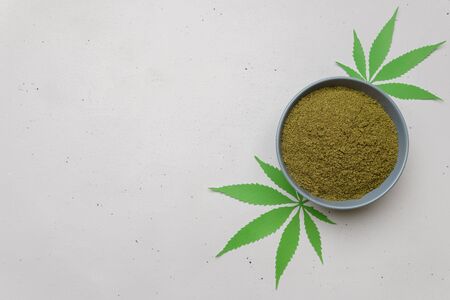 Bowl with hemp flour and leaves on a light concrete table. Top view with copy space.の写真素材