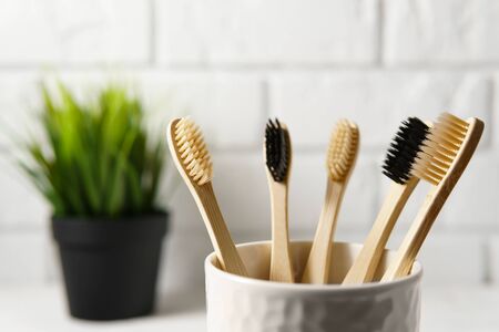Close up of several biodegradable bamboo toothbrushes in a white glass on a brick wall background. Image with copy space, horizontal orientation. Zero waste concept.の写真素材