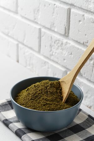 Hemp Flour in a gray ceramic bowl with a wooden spoon, cellular textiles on a light concrete surface. Image contains copy space, vertical orientation.の写真素材