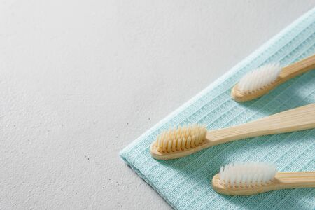 Three bamboo toothbrushes with light blue towel on a gray concrete table. Zero waste concept. Eco friendly personal care products. Image contains copy space. No plastic.の写真素材
