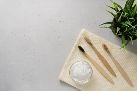 Three bamboo toothbrushes, tooth powder and towel on a light gray concrete background. Concept no plastic and zero waste. Top view, copy space.の写真素材