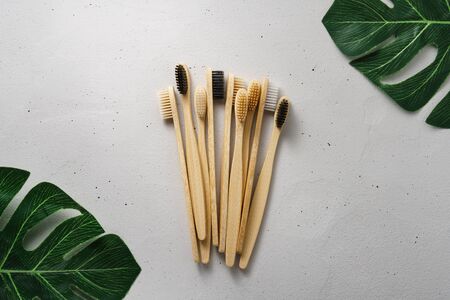 A pile of biodegradable bamboo toothbrushes and leaves on a light gray concrete background. Top view with copy space. Zero waste and no plastic concept.の写真素材