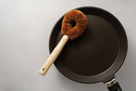 A brush made of coconut flakes with a bamboo handle over the pan. Biodegradable kitchen accessories. No plastic concept.の写真素材