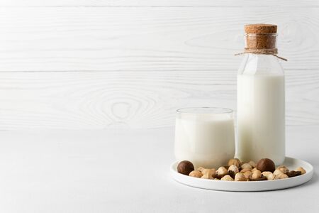 Dairy-free milk. Macadamia nut milk in a glass cup and a bottle on a white background. Dairy products without lactose. Copy space.の写真素材