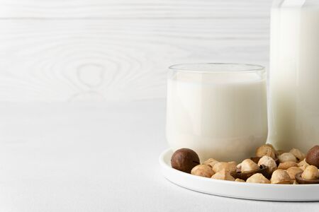 Dairy-free milk. Macadamia nut milk in a glass cup on a white background. Dairy products without lactose. Copy space, close-up.の写真素材