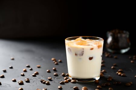 Iced coffee in a glass cup on a black concrete table. Horizontal orientation, copy space.