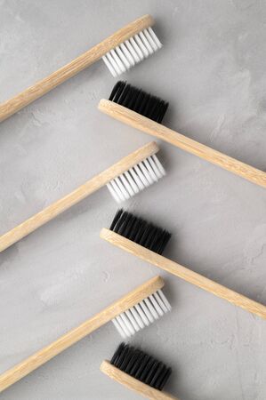 Zero waste concept. Set of eco friendly bamboo toothbrushes on a gray concrete background. Flat lay, vertical orientation. Layout natural organic hygiene products.の写真素材