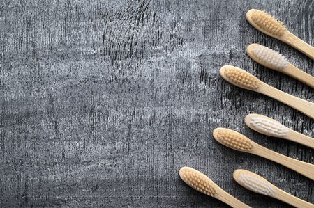 Zero waste and no plastic concept. Set of eco friendly bamboo toothbrushes on a dark gray surface. Top view, copy space, horizontal orientation. Layout natural organic hygiene products.の写真素材