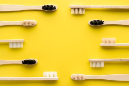 Zero waste concept. Set of eco friendly bamboo toothbrushes on a bright yellow background. Flat lay, copy space, horizontal orientation. Layout natural organic hygiene products.の写真素材