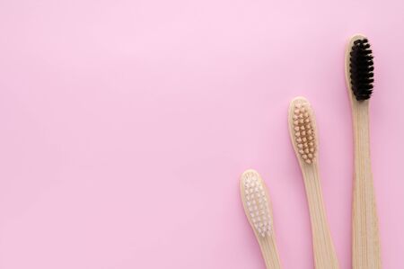 Zero waste and no plastic concept. Three eco friendly bamboo toothbrushes on a pink surface. Top view, copy space, horizontal orientation. Layout natural organic hygiene products.の写真素材