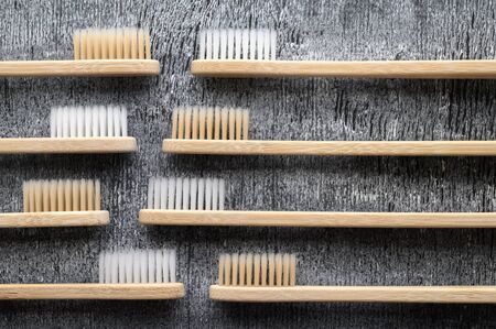 Zero waste concept. Set of eco friendly bamboo toothbrushes on a gray wooden background. Top view, horizontal orientation. Layout natural organic hygiene products. No plastic.の写真素材