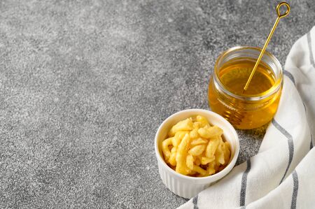 National food cuisine of the Middle East. White ramekin with chak chak and honey in a jar on a gray table. Horizontal orientation, copy space.の写真素材
