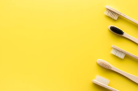 Zero waste concept. Set of eco friendly bamboo toothbrushes on a bright yellow background. Flat lay, copy space, horizontal orientation. Layout natural organic hygiene products.の写真素材